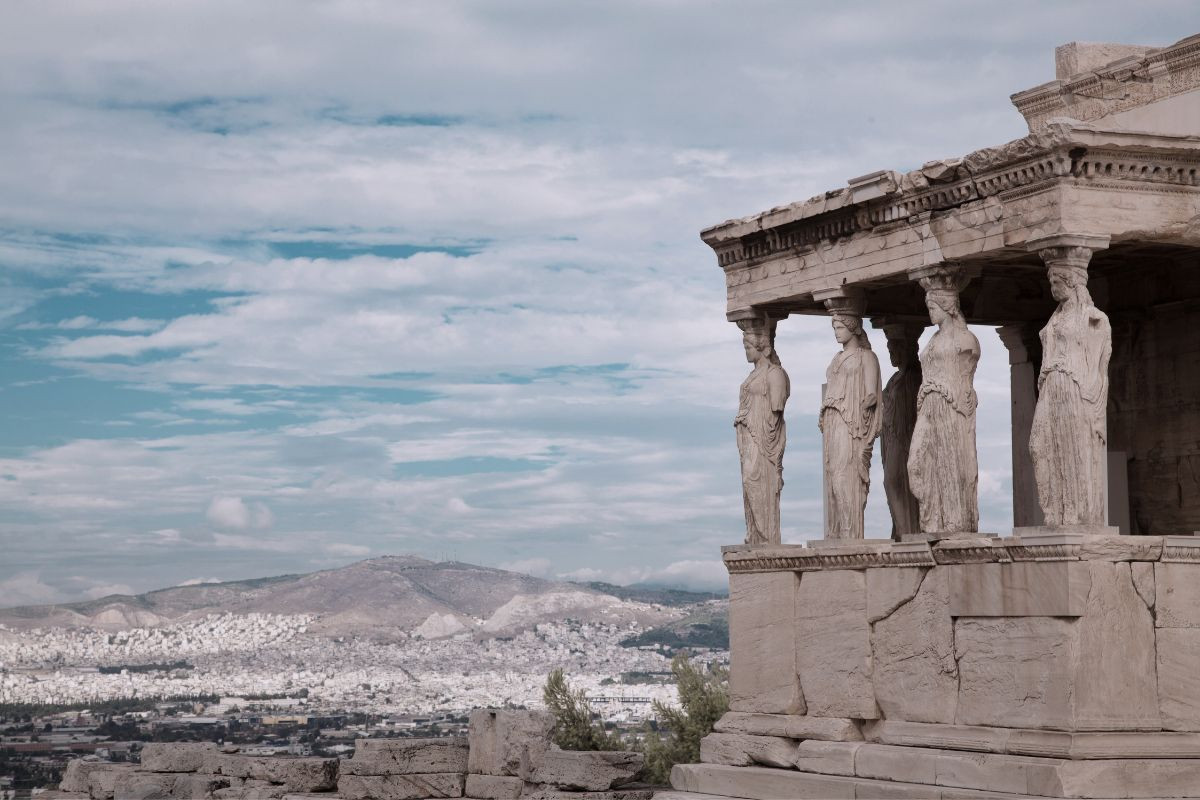Caryatid statues standing in a row with the cityscape in the background.